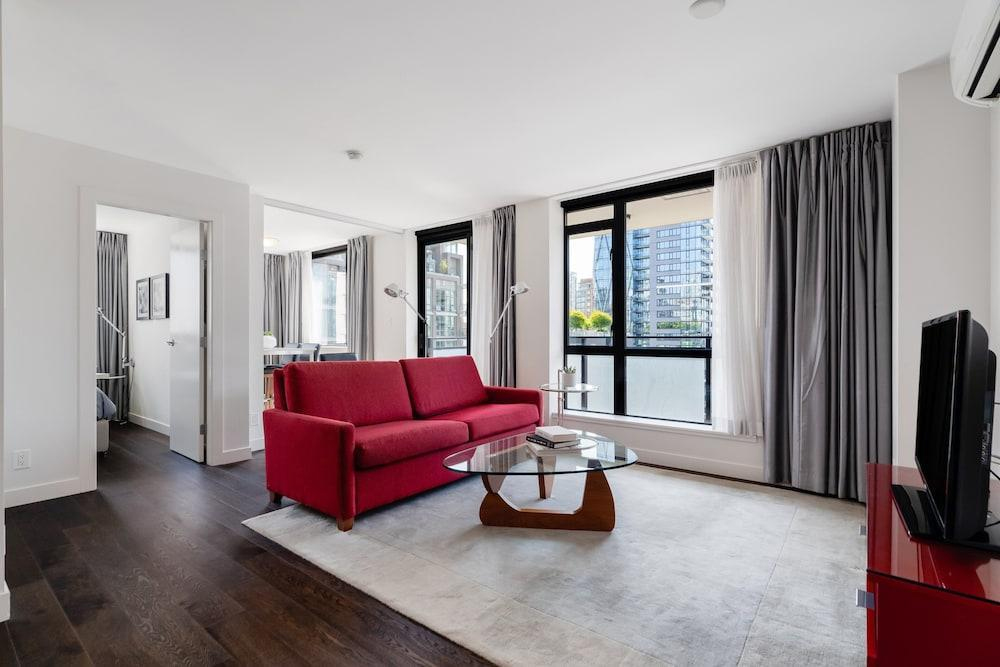 Concept image: a bright furnished apartment living room with a red sofa and city views